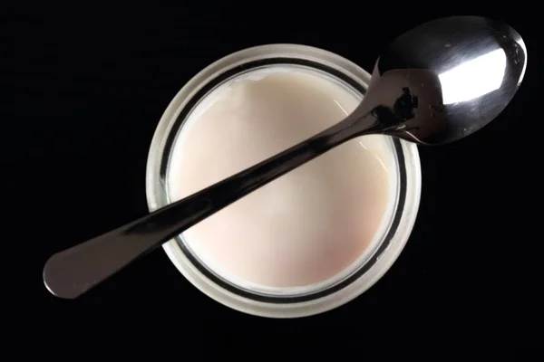 酸奶在打开小玻璃瓶与勺子在黑色背景 直接在上面 — 图库照片