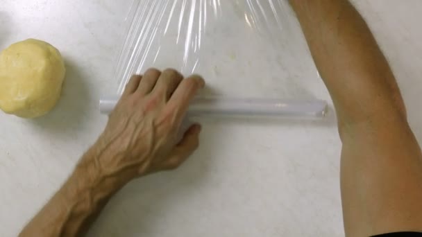 男性の手をカバーするプラスチック製のラップで生地の上から見る — ストック動画