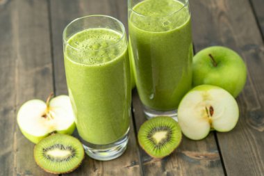 Kivi ve elma güler yüzlü ahşap masa üzerinde iki bardak