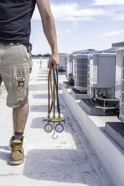 Hvac tech holding gauges next to air conditioners