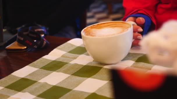 Menina está segurando uma xícara de café quente em um café — Vídeo de Stock