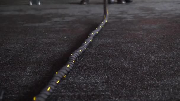 Крупный план кроссфит тренировки черной веревки в фитнес-зал на каучуковом полу — стоковое видео