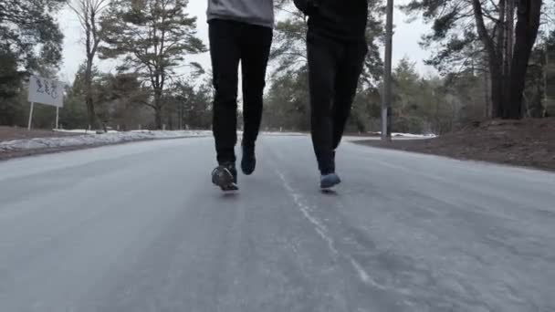 Двоє спортсменів біжать до камери в парку. Крупним планом. Взуття для бігу — стокове відео