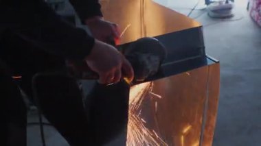 Adam dairesel testere çalışıyor. Sıcak metalden kıvılcım uçar. Adam çelik üzerinde çalışıyordu. El aleti yakın çekim.
