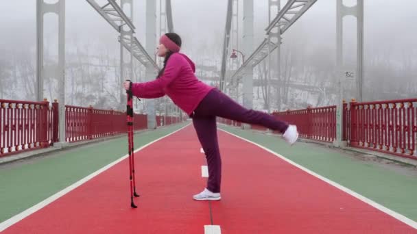 Nordic Walking. junge pausbäckige Kaukasierin beim Wandern mit sich streckenden Nordic-Stöcken. Schuss nach vorne. — Stockvideo