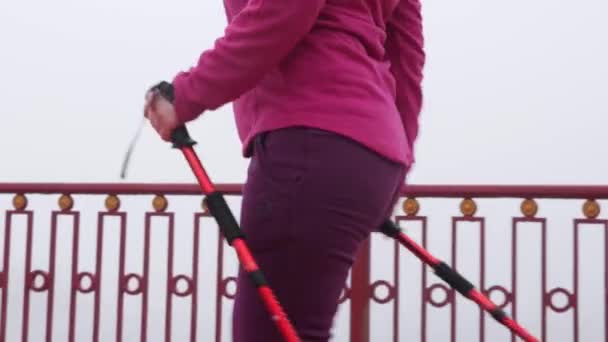 Nordic walking. Young chubby Caucasian woman hiking with the Nordic poles. Close up Side Follow Shot. — Stock Video