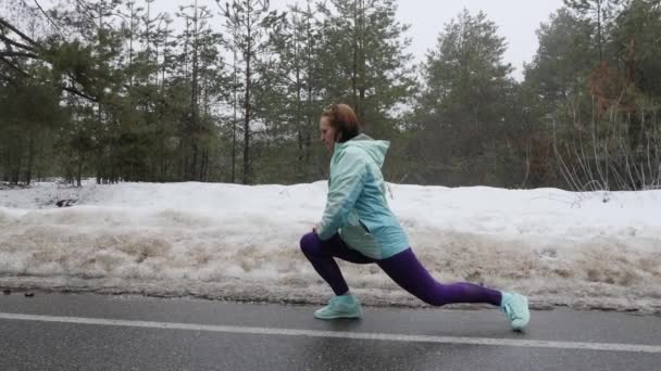 老白人妇女在雪冬公园跑步前热身伸展运动。侧射. — 图库视频影像