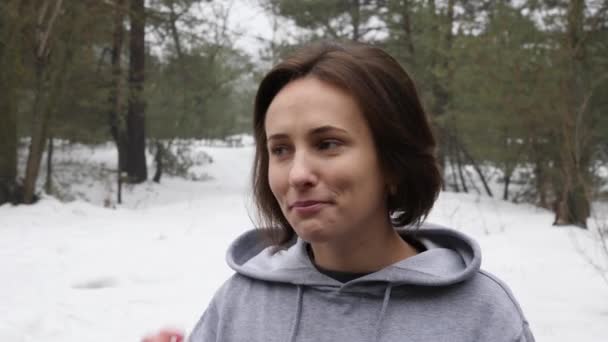 Unga attraktiva kaukasiska flicka sätter i hennes hörlurar innan du kör i den snöiga parken på vintern. Närbild front shot. — Stockvideo