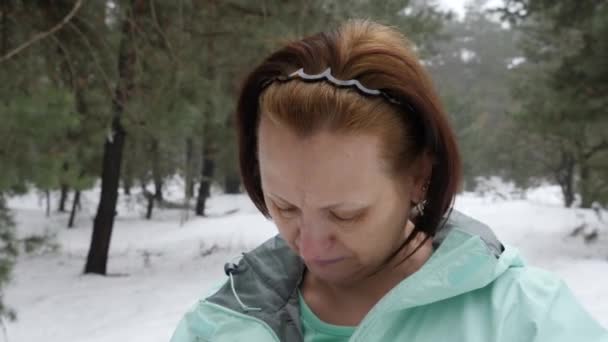 Senior velha mulher caucasiana fecha o casaco antes de correr no parque de inverno nevado. Fechar foto da frente — Vídeo de Stock