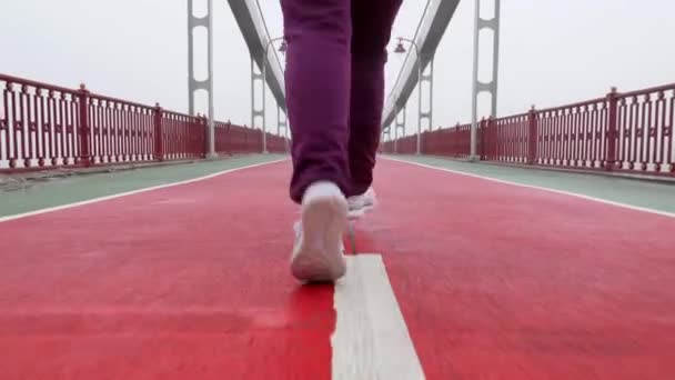 Primer plano de la espalda de una chica corriendo de la cámara en zapatos blancos. Movimiento lento — Vídeo de stock