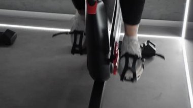 Sabit bisiklet üzerinde kardiyo Bisiklet iplik egzersiz yapıyor fit kız görünümü yakın. Dönme bisikleti üzerinde pedlama yakın