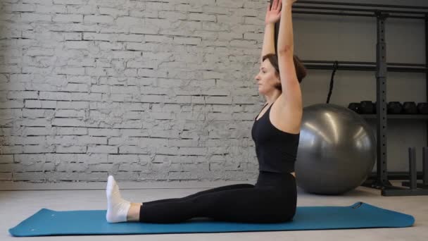 Йога мат молода атлетична жінка розтягує стегно, розтягує м'язи, м'язи ніг в приміщенні спортзалу. Вправи для розтягування — стокове відео