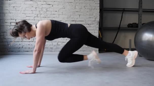 Atlético bela mulher faz prancha de corrida como parte de sua aptidão Cruz, Musculação Ginásio Rotina de Treinamento. Vista frontal close up — Vídeo de Stock