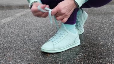 Yaşlı beyaz kadın, karlı kış parkında Koşmadan önce ayakkabılarını bağlıyor. Yan atış yakın