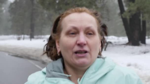 冬に雪の公園で走っている年長の白人女性前にクローズアップショット。スローモーション — ストック動画