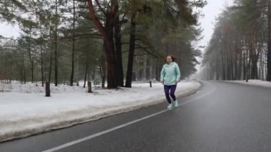 Yaşlı eski kafkas kadın kulaklıklar ile kış aylarında karlı parkta çalışan. Ön takip çekimi.