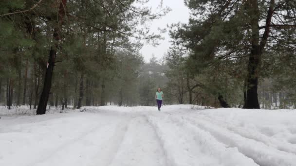 Слід бігти. Старша стара кавказька жінка, що працює в лісі на снігу. Фронт стежити постріл. Повільний рух — стокове відео