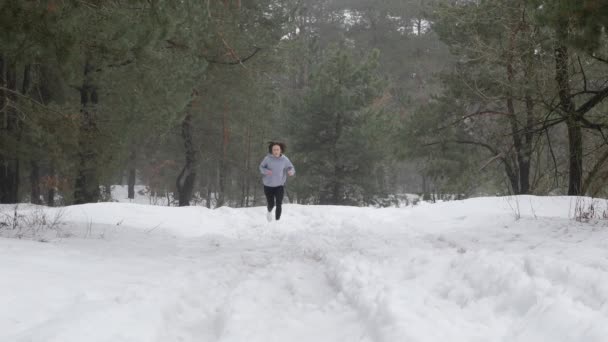 Бег по тропе. Молодые привлекательные кавказские девушки бегут в лесу по снегу. Передний статический выстрел. Slow Motion — стоковое видео