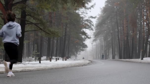 Mladá přitažlivá Kavkazská dívka, která v zimě běží v zasněženém parku. Zadní statická střela — Stock video