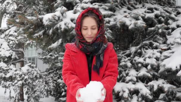 Mooie jonge Kaukasische vrouw in rode jas spelen met sneeuw in de winter buiten — Stockvideo