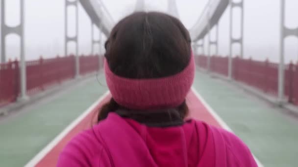 Young chubby caucasian girl running on a bridge. Back follow shot. Slow motion. Purple outfit — Stock Video