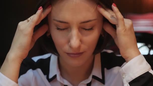 Close up view of young woman closing her eyes, touches her forehead, having a headache, massages her temples. Stress, conflict, pain. Female portrait — Stock Video