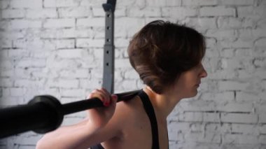 Güzel genç atletik sportif kadın geri squat spor salonunda kardiyo egzersiz yapıyor. Ön yakın görünüm
