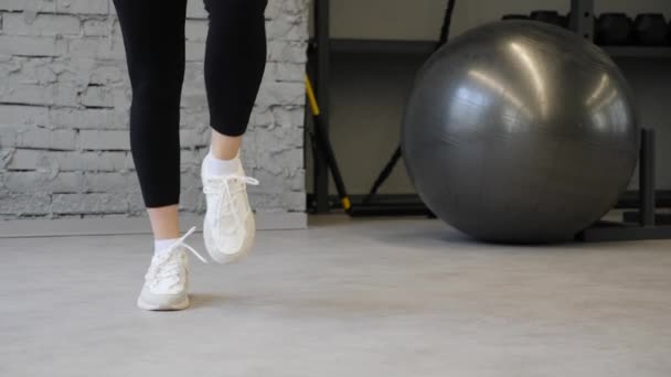 Közeli nő fitness fehér cipőt. Gyakorlása az edzőteremben vagy otthon, cardio edzés, részlet a szép lábak fut. Farag, forma lábak edzés. Sporswoman képzés cipők.