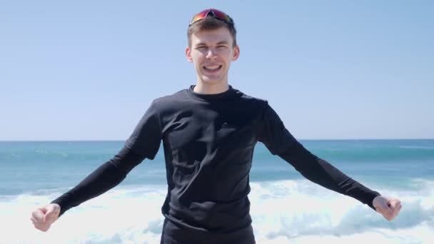 Joven Fit confiado hombre caucásico muestra sus músculos posando en la playa. Movimiento lento — Vídeo de stock