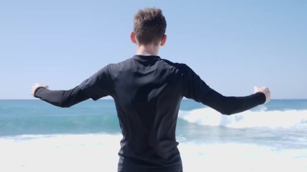 Joven Fit confiado hombre caucásico muestra sus músculos posando en la playa. Vuelta atrás — Vídeos de Stock