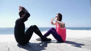 Plaj yakınında oturan mutlu genç adam ve kadın yüksek Fives. Dalgalar kayalara dalıyor. Genç çift yüksek beş. Yavaş hareket