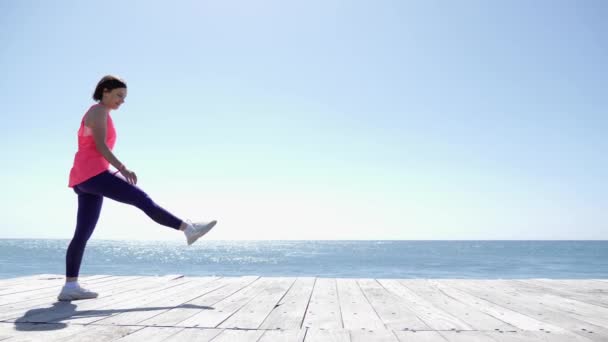 Jovem mulher atlética se encaixa faz cartwheel na praia. Ondas fortes atingindo a costa. Movimento lento — Vídeo de Stock