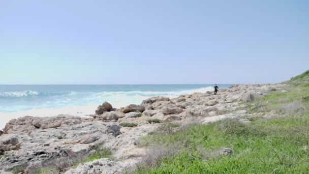 젊은 슬림 스포티 한 남자가 바위 흔적을 실행 합니다. 바다를 치는 강한 파도. — 비디오