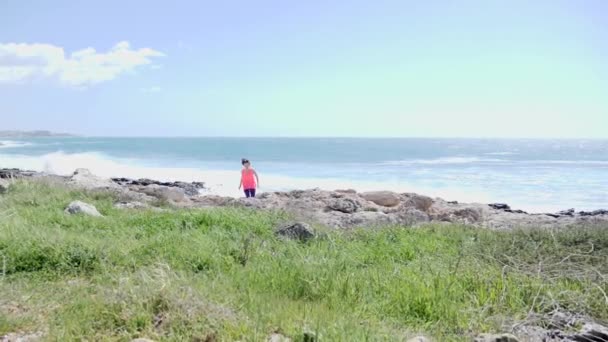Μια νεαρή γυναίκα που κινείται σε ένα μονοπάτι προς την κάμερα. Ισχυρή θυελλώδης θάλασσα στο παρασκήνιο. Αργή κίνηση — Αρχείο Βίντεο