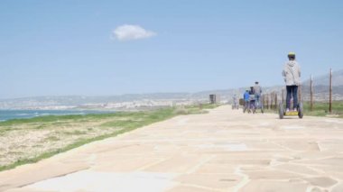 Güneşli rüzgarlı bir günde plaj boyunca Segway elektrikli scooter sürme turistler grubu. Yavaş hareket