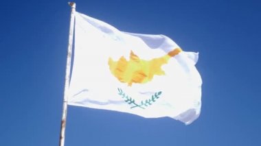 Kıbrıs bayrağı bir kutup üzerinde rüzgar çırparak. Mavi gökyüzü ve Kıbrıs bayrağı. Yavaş hareket