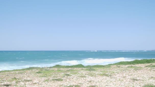 Joven corredor en forma en un sendero a lo largo de la playa vistiendo traje deportivo negro — Vídeos de Stock