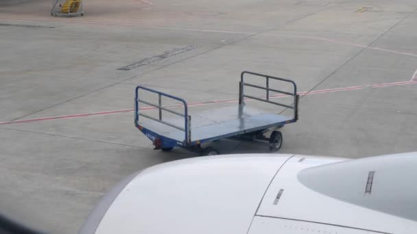 Lege bagagewagen in de luchthaven. Uitzicht vanuit het vliegtuig door het raam — Stockvideo