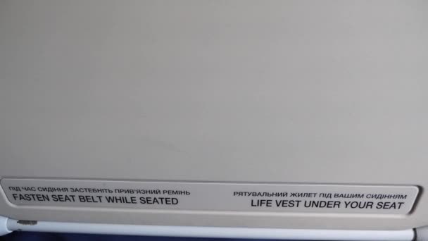 Aperte o cinto de segurança enquanto estiver sentado e colete salva-vidas sob o sinal do assento no avião — Vídeo de Stock