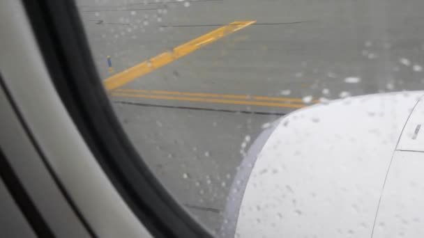 Uitzicht vanuit het bedden venster met regendruppels op de landingsbaan en vliegtuigmotor — Stockvideo