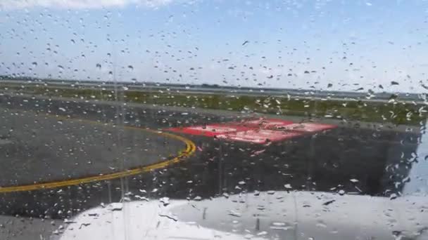 Вид на взлетно-посадочную полосу аэропорта через окно самолета перед вылетом с капли дождя — стоковое видео