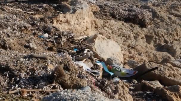 Playa rocosa pulsada llena de plástico y basura. Concepto de problemas ambientales. Movimiento lento — Vídeo de stock