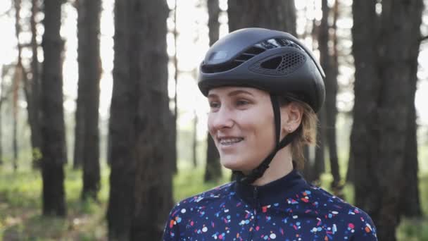 Портрет молодой привлекательной девушки, надевающей очки перед езда на велосипеде в черном шлеме и синей майке. Концепция велосипедного спорта — стоковое видео