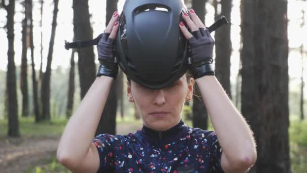 Zelfverzekerde jonge fietser vrouw zet op helm op zoek naar de camera. Triathlon concept. Slow Motion — Stockvideo