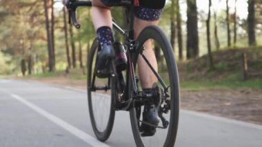 Fit kafkas triathlete kız parkta bir bisiklet sürmek. Pedal çevirin. Bacak kasları kapanır. Triatlon konsepti. Yavaş çekim