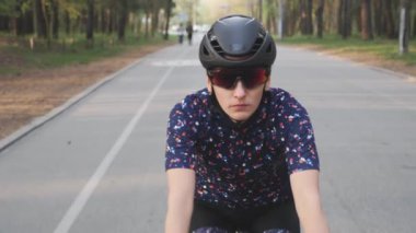 Kadın bisikletçi parkta bisiklete biniyor. Ön takip atışı. Bisiklet konsepti. Yavaş çekim