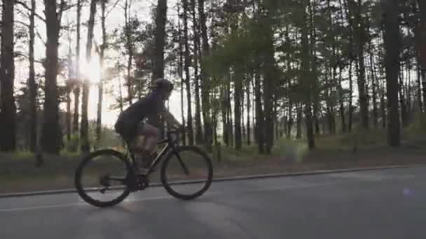 Mladá krásná dívka cyklistka jezdí na kole v části. Následujte záběr se sluncem mezi stromy na pozadí. Cyklistický koncept — Stock video