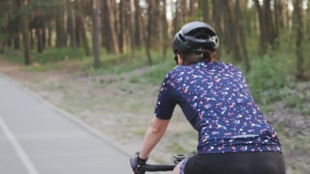 Spor bisikletçi kadın parkta bisiklete biniyor. Arka taraf takip atış. Bisiklet konsepti — Stok video
