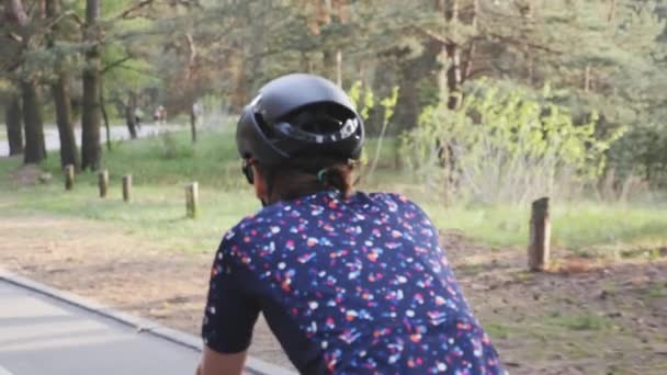 Primer plano de la bicicleta ciclista femenina en un parque con casco negro y jersey azul. Movimiento lento — Vídeos de Stock
