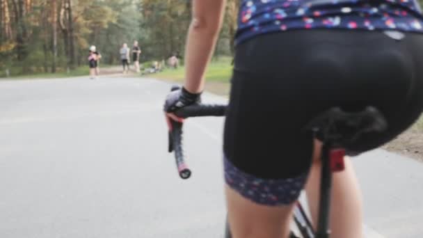 Mujer triatleta ciclista pedaleando bicicleta en el parque. Cierra los pedales en movimiento. Concepto de triatlón . — Vídeo de stock